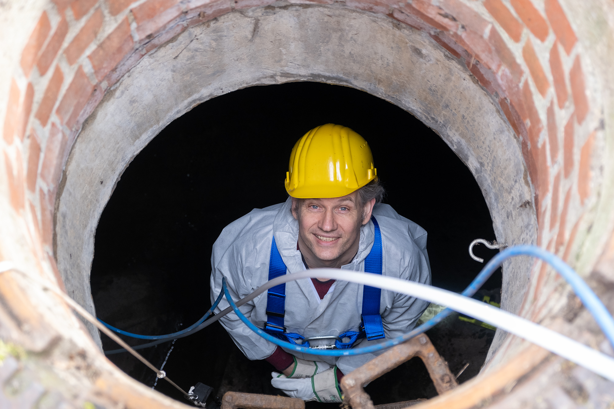 A scientist standing in the storm sewer and smiling at us through the drain
