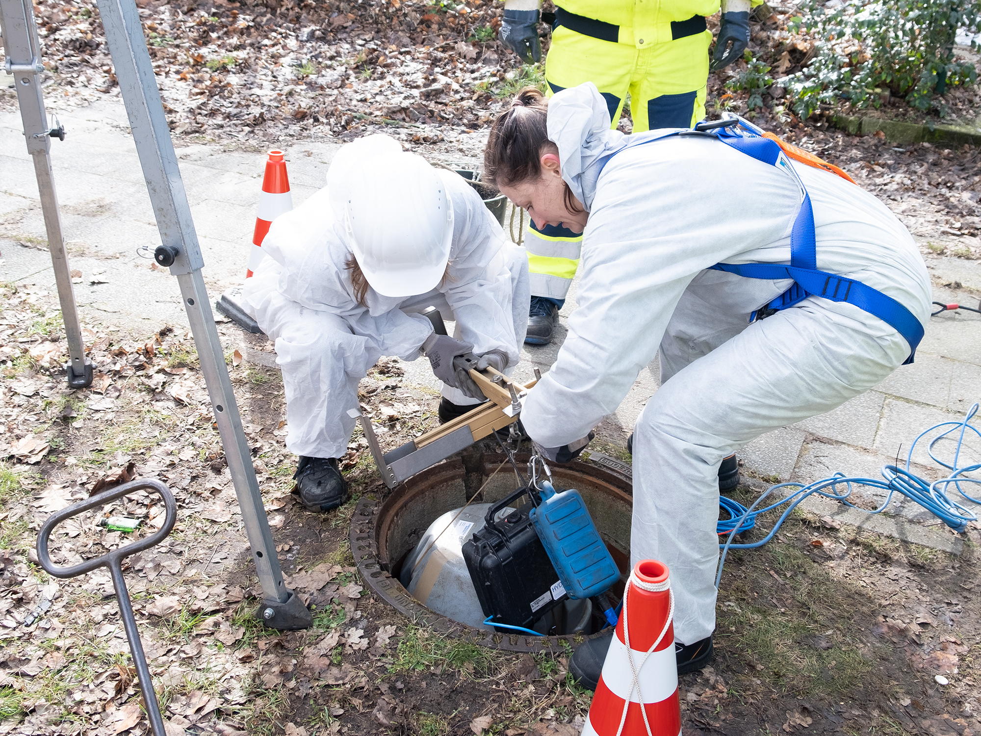 Scientists place the instruments in the manhole using a supporting cross